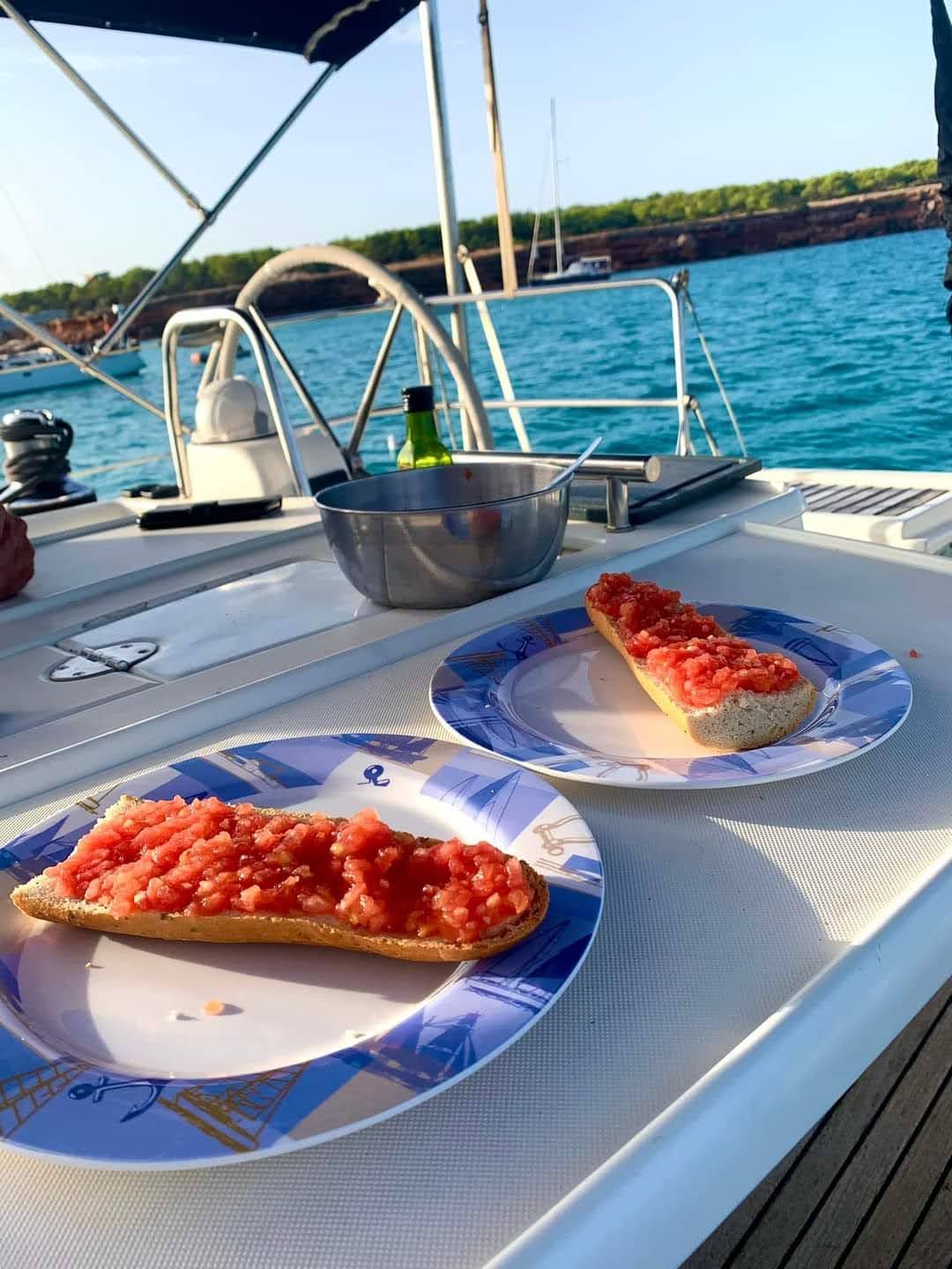 Pan con tomate preparado a bordo, servido en la cubierta del velero
